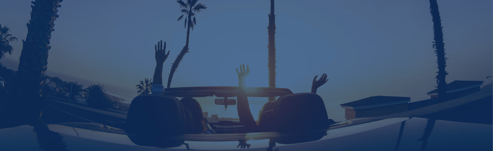 people parked in a convertible car at sunset near beach