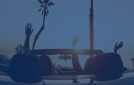 people parked in a convertible car at sunset near the beach