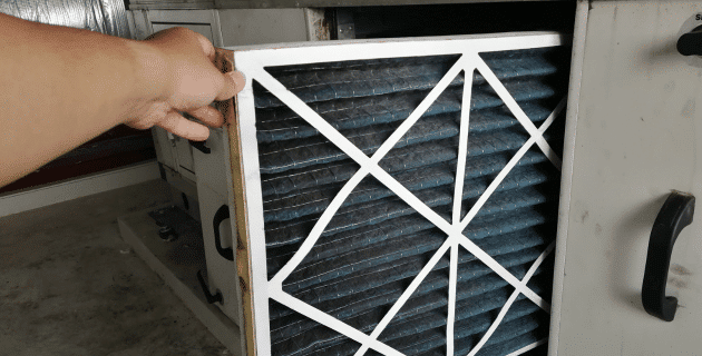 hand pulling air filter from furnace
