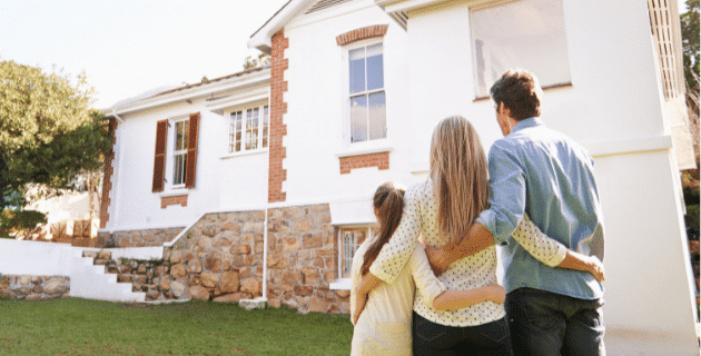 family arm in arm looking at house